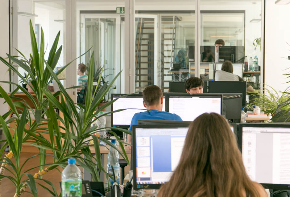 Mitarbeitende der Projektron GmbH sitzen an ihren Schreibtischen und arbeiten am Computer